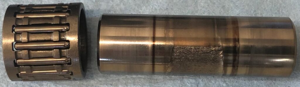 Needle roller cage on a piston pin showing the rollers and the worn running track
